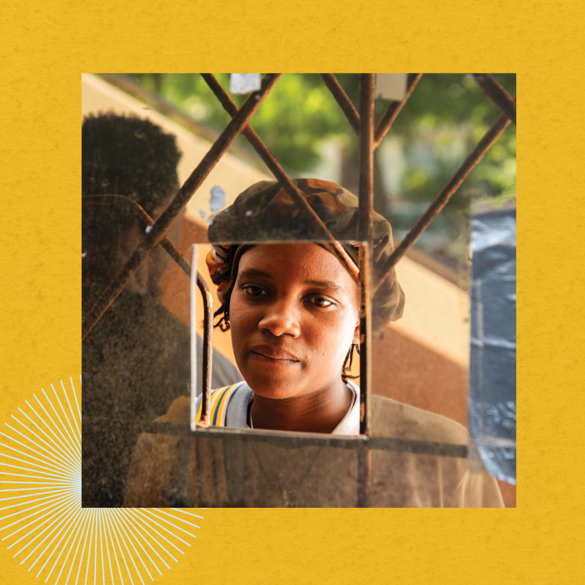 A woman looks into the window of St. Boniface Hospital's pharmacy. The background of the image is bright yellow.