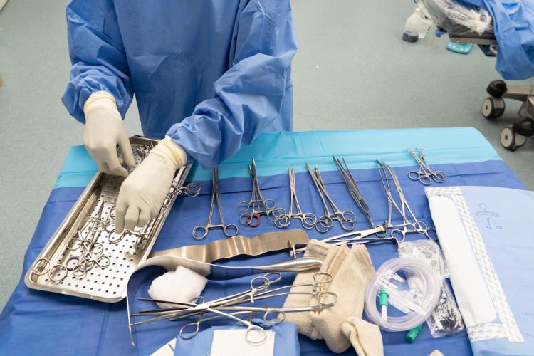 A staff member sorts through a table full of many different kinds of surgical equipment. 