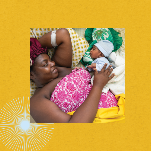 A Haitian mother lays in bed similing at her newborn baby, who she reaches out and touches gently.
