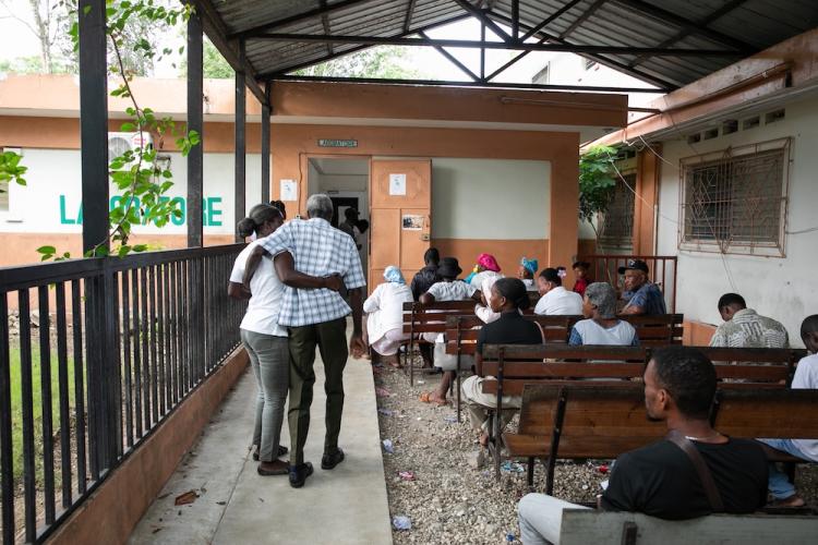 A Haitian woman helps an older Haitian man into St. Boniface Hospital's pharmacy