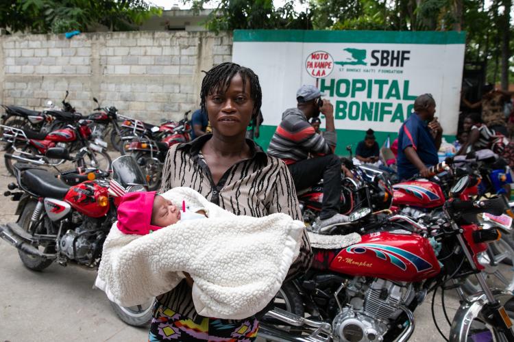 A Haitian mother cradles her newborn baby outside St. Boniface Hospital.