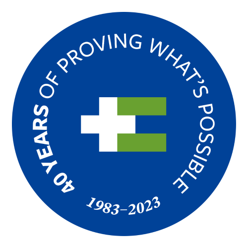 A dark blue circle with a bright green equal sign and a white plus sign in the middle. Around the outside are the words, "40 years of proving what's possible 1983-2023"