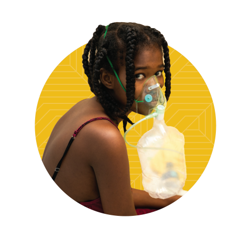 A Haitian girl looks over her shoulder as she breathes medical oxygen through a medical mask and bag.