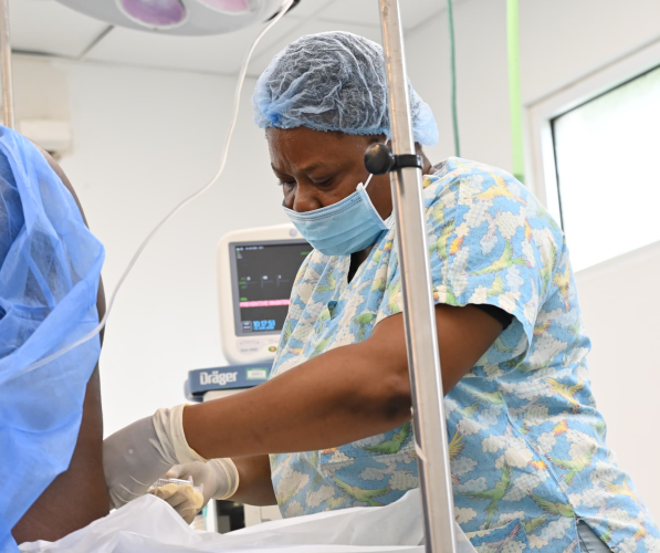 A Haitian woman nurse anethesist performs a procedure on a patient's back.