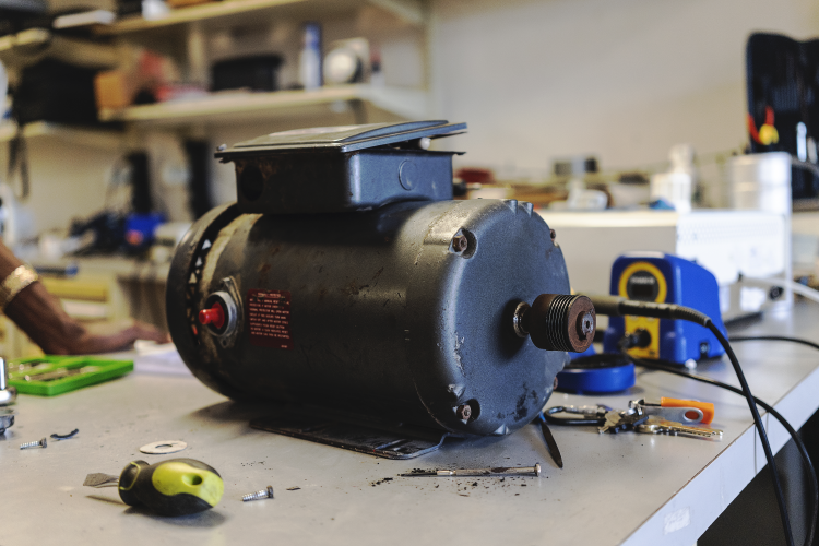 The motor of an oxygen concentrator sits on a table in a biomedical equipment repair workshop.