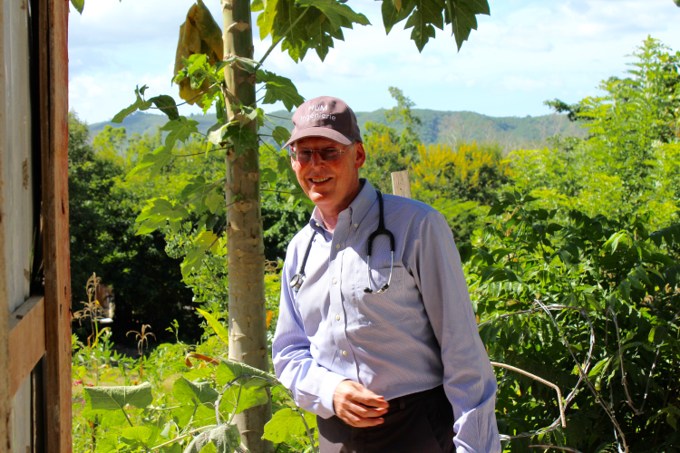 Dr. Farmer at St. Boniface Hospital in front of the lush green vegetation of Fond des Blancs.