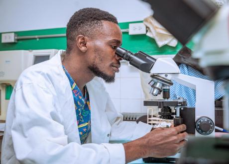 A male Haitian laboratory technician looks into a microscope at our partner facility in Dame Mare, Haiti.