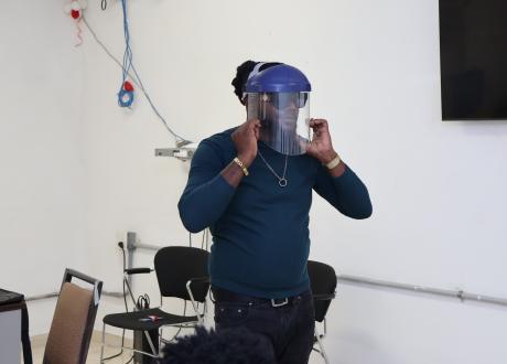 A waste management trainer shows how to properly don a personal protective mask.