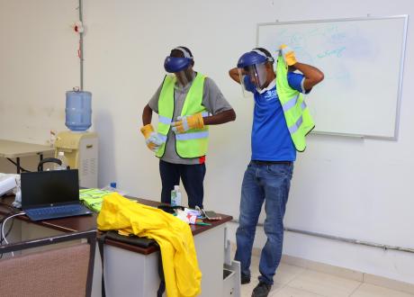 Two employees don PPE face masks and reflective vests.