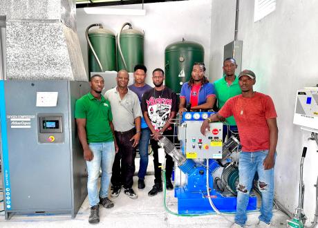 Haitian repair technicians gather around an oxygen generation system for a group photo