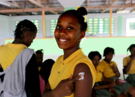 Girl in yellow shirt smiles after HPV vaccine shot