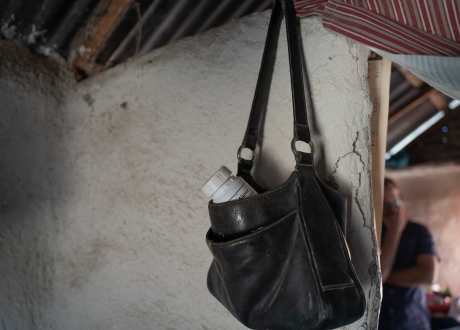 Marie's medication hangs from a bag on the wall of her home.