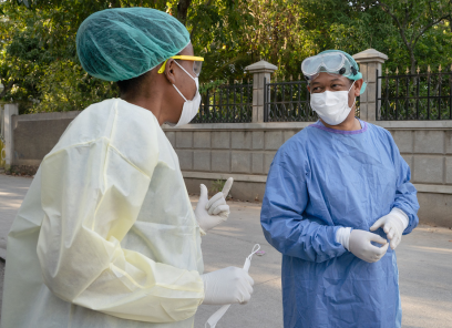 Two doctors talk to each other in the street while personal protective equipment.