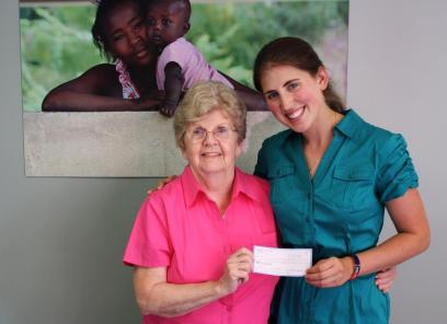Leader of students for Haiti handing Nanette, the St. Boniface co-founder, a check 
