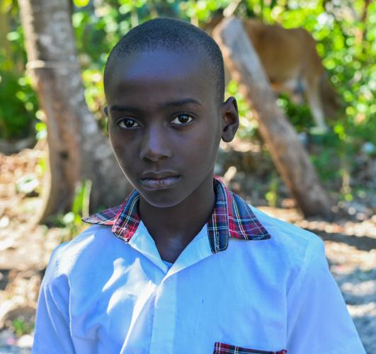 Head and shoulders of a 10-year-old Haitian boy in crisp white button-down shirt, gazing at the camera.