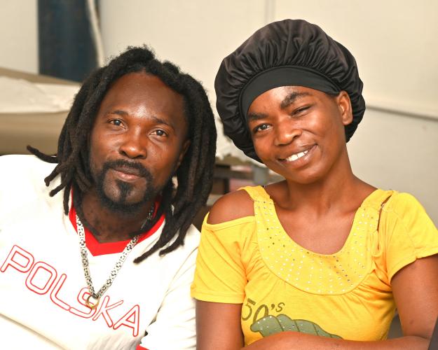 A Haitian man and woman sitting side by side, each leaning toward the other and smiling with great affection, openness, and warmth.