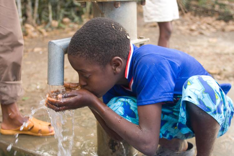 boy drinking water from well pump