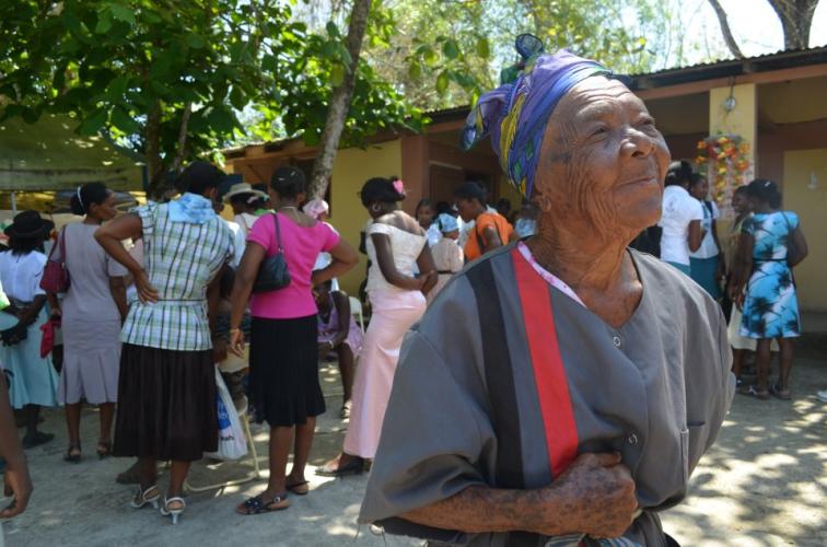 Elderly woman smiling with a crowd of other women in the background