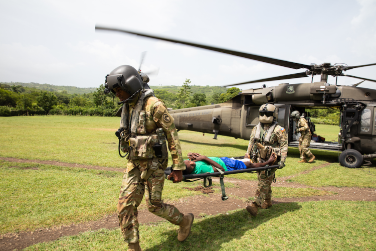 Earthquake survivor Dorval Wilson is carried out of helicopter on a stretcher by two pilots after the August 14, 2021 earthquake in southern Haiti.