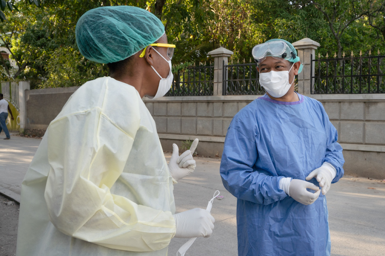 Two doctors talk to each other in the street while personal protective equipment.