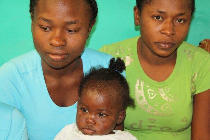 Two women sitting, one has a baby on her lap