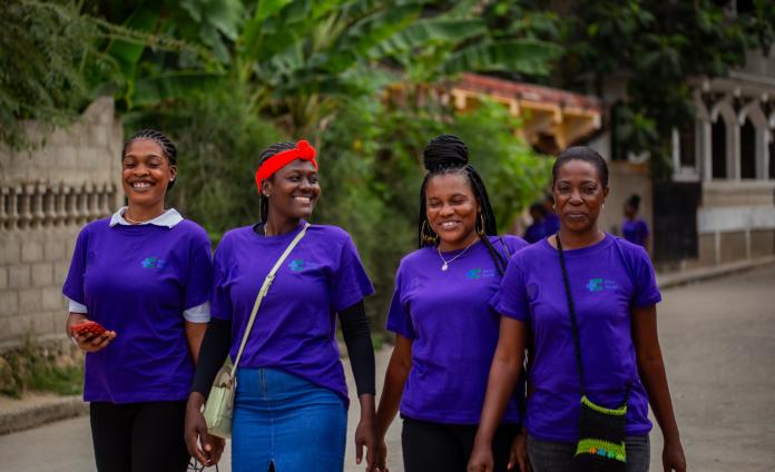 A group of four women Kore Sante team members walk down the street and smile.