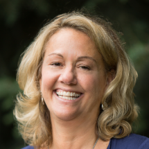 A headshot of Judi Gale smiling and wearing a white shirt and blue cardigan.