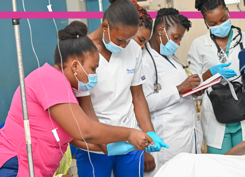 A group of woman Haitian clinicians tend to a patient in SBH's emergency care center.