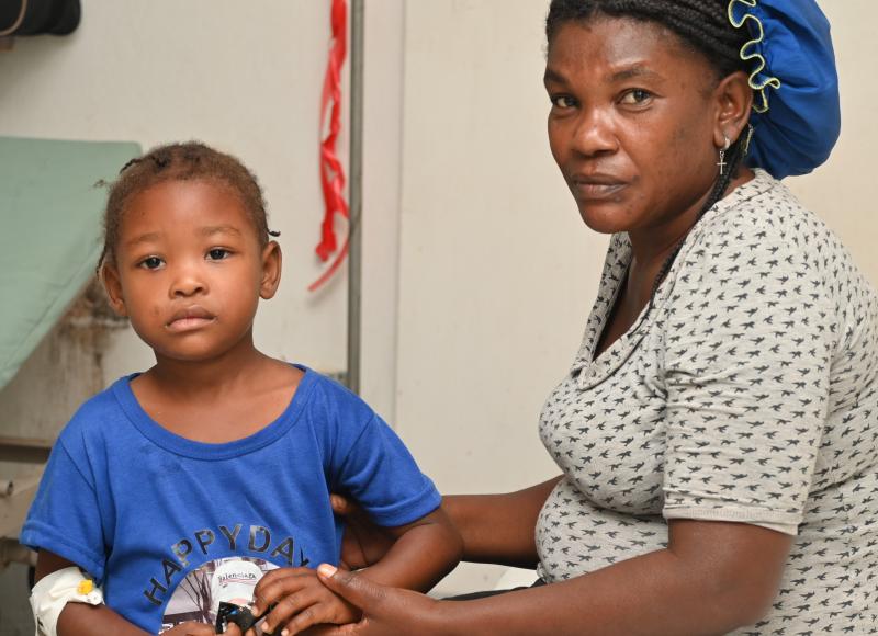 A young Haitian girl stands next to her mother in a room at SBH.