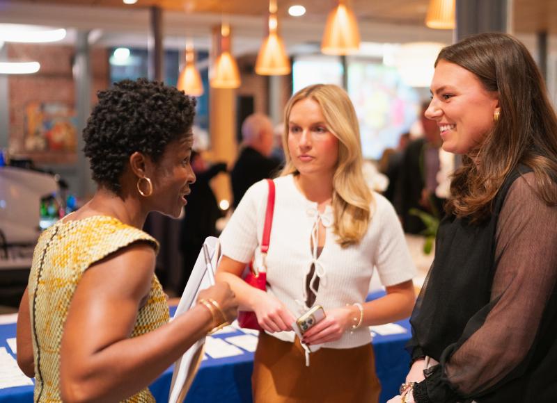A group of attendees talk animatedly at HEI's 2025 celebration.
