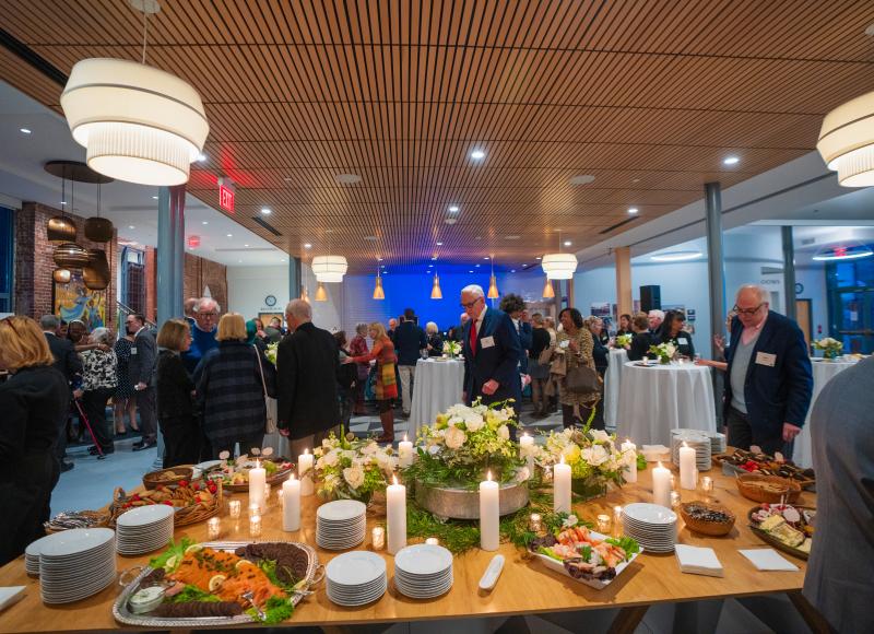 A table full of food at HEI's 2025 celebration surrounded by lots of guets.