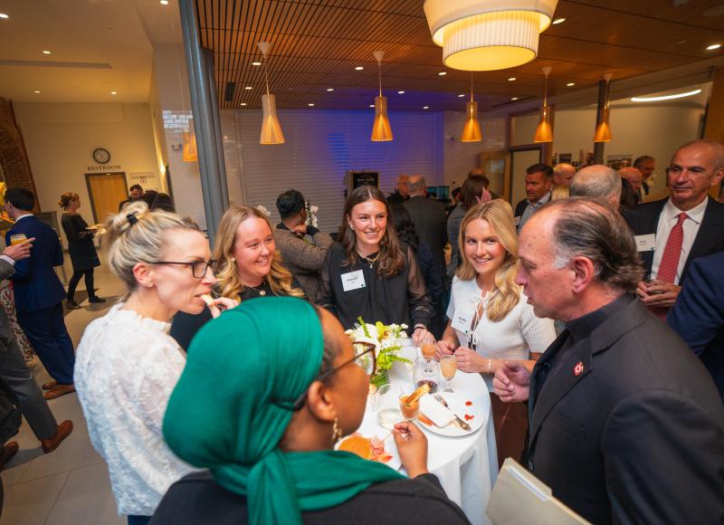 A group of attendees talk animatedly around a small table at HEI's 2025 celebration.