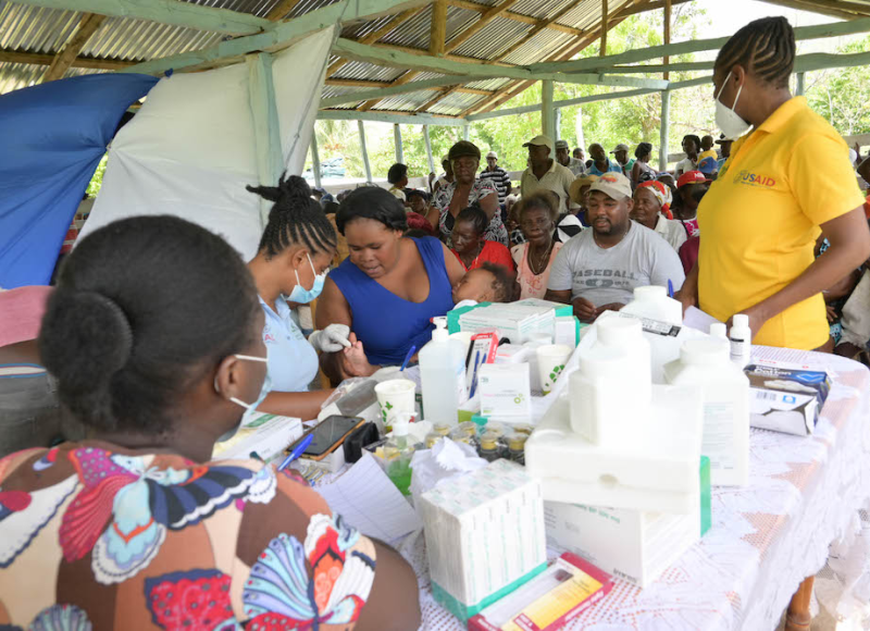 Community health nurses provide care to a large crowd of patients at an earthquake mobile clinic.