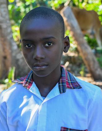 Head and shoulders of a 10-year-old Haitian boy in crisp white button-down shirt, gazing at the camera.