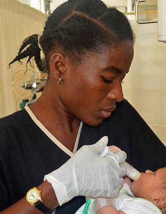 Nurse feeding a newborn with formula