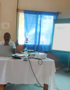 Dr. Bertony Guerrier sits behind a table as he lectures about maternal health and spinal cord injuries.