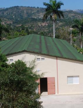 Aerial view of Villa Clinic, a clean rectangular concrete building high in the mountains, with palm trees behind.