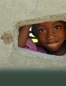 Young girl looking through a hole in the wall