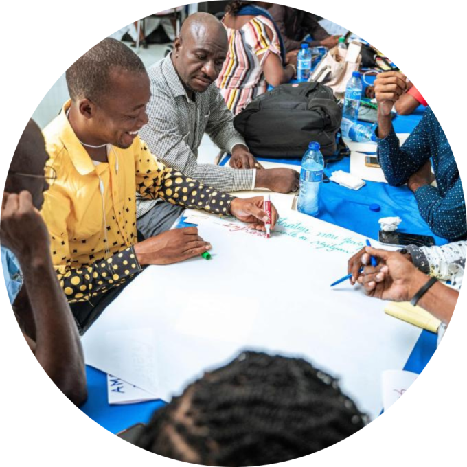 A group of Haitian clinicians talk animatedly around a table at a conference.