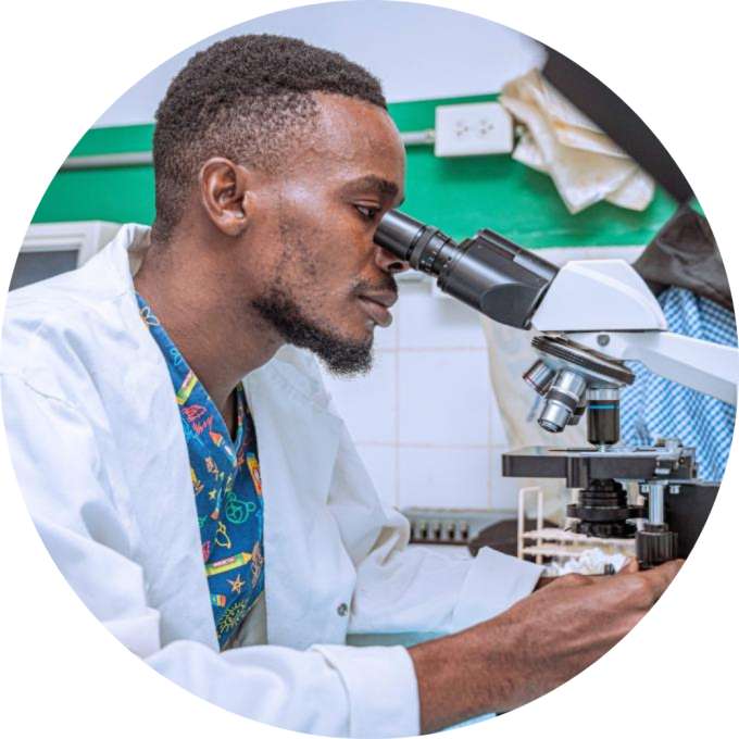 A Haitian laboratory worker looks through a microscope.