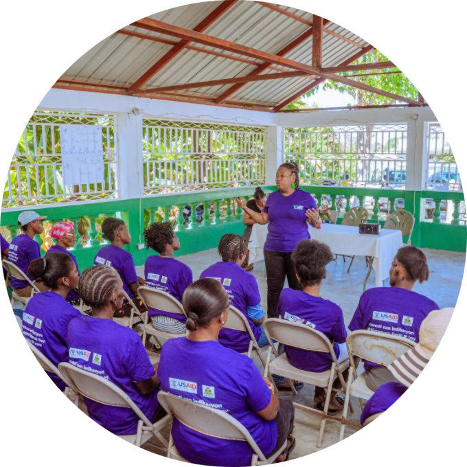 Haitian women gather for a community health event. Everyone is wearing purple shirts.