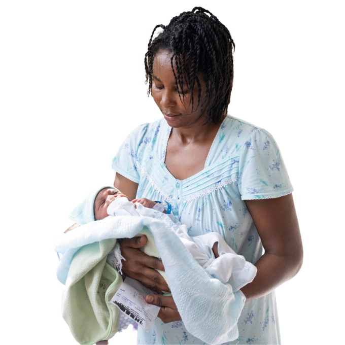 A Haitian woman in a light blue dress cradles her newborn baby, who is swaddled in blankets.